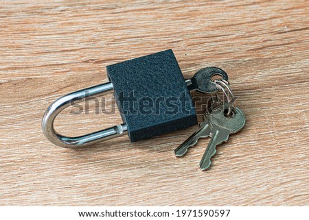open iron padlock with keys in the keyhole on the wooden surface concept prohibition security restriction High quality photo