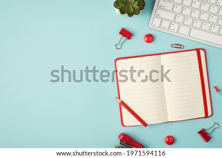 Top view photo of open red planner binders pins clips stapler plant and keyboard on isolated pastel blue background with copyspace