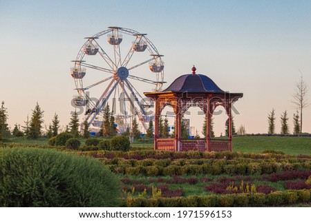 A delightful gazebo and observation wheel in a spring park. Royalty-Free Stock Photo #1971596153