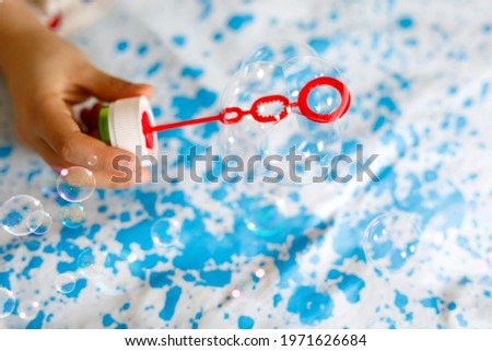 Closeup of child playing with soap bubbles at home. Hands of kid, boy or girl