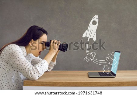 Side profile view astonished lady looking in binoculars at rocket flying out laptop computer screen. Surprised girl watching accelerated growth of modern digital startup of successful business rival Royalty-Free Stock Photo #1971631748