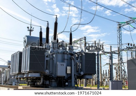 High voltage transformer against the blue sky. Electric current redistribution substation Royalty-Free Stock Photo #1971671024