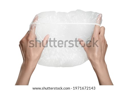 Woman holding transparent shower cap on grey background, closeup Royalty-Free Stock Photo #1971672143
