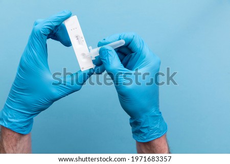 Doctor in blue gloves using a lateral flow covid-19 testing kit Royalty-Free Stock Photo #1971683357