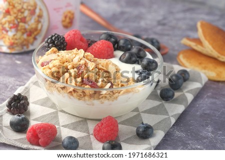 Granola and berries in bowl on pink background 