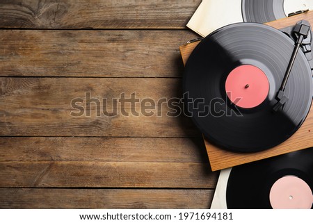 Modern player and vinyl records on wooden background, flat lay. Space for text Royalty-Free Stock Photo #1971694181