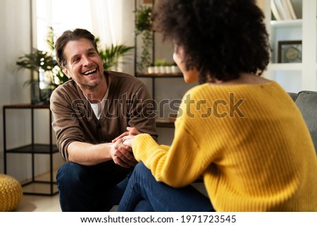 Young couple sitting and talking at home. Woman and man flirting and laughing	