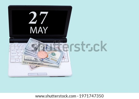 27th day of may. Laptop with the date of 27 may and cryptocurrency Bitcoin, dollars on a blue background. Buy or sell cryptocurrency. Stock market concept. Spring month, day of the year concept.