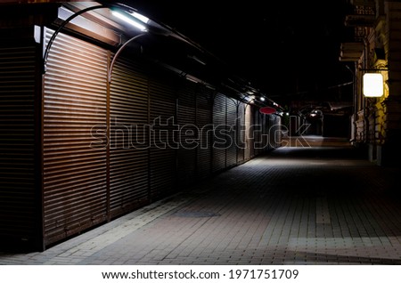indoor empty street market steel roller shutters. night deserted lane. street vendors Royalty-Free Stock Photo #1971751709