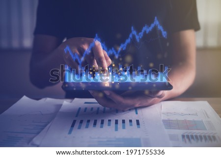 Businessman analyzing financial, fund, account data from growing investments. Virtual graph reporting using digital technology. Man touching tablet at working room. Business finance growth concept.