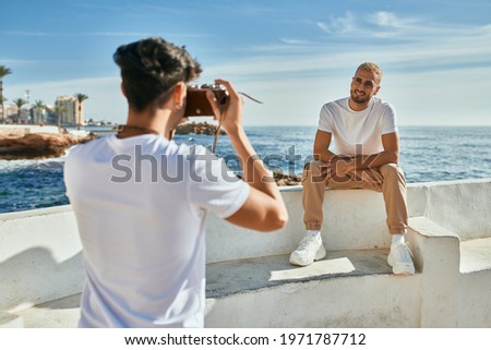 Man taking photos of his boyfriend in front of the sea.