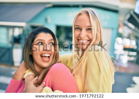 Two beautiful and young girl friends hugging together with love