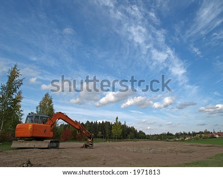 Excavator preparing golf field and a beautiful outumn sky, view