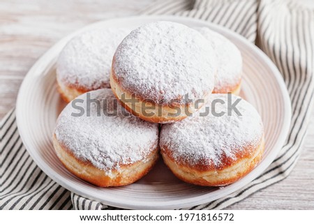 Delicious strawberry jam filled berliner doughnuts on white plate with napkin on wooden table top overhead Royalty-Free Stock Photo #1971816572
