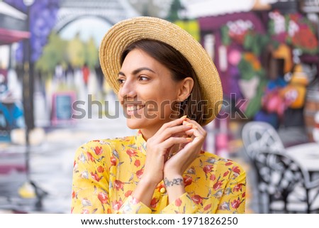 Outdoor fashion portrait of woman in yellow summer dress on background of street wall colorful art picture at summer time