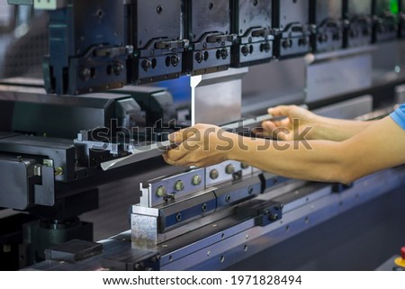The technician operator working with hydraulic press brake bending machine. The sheet metal working operation by skill operator. Royalty-Free Stock Photo #1971828494