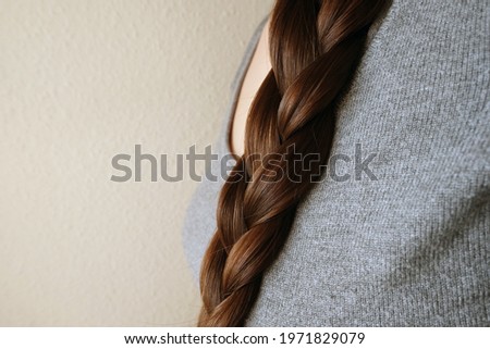 young woman, brunette, braids her long beautiful hair in a thick braid, concept of hygiene, hair care, traditions