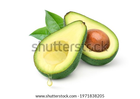 Avocado oil dripping from half avocado fruit with leaves isolated on white background.