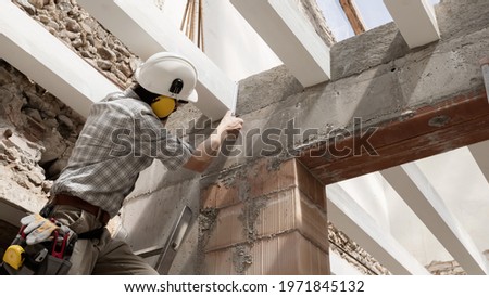 man at work, construction worker wear a helmet, check the measurements and distances of the beams at the base of the foundations of the second floor of house, in renovation building site background Royalty-Free Stock Photo #1971845132