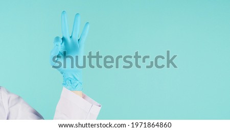 Hand do A ok hand sign.Man wear doctor gown and blue medical glove on mint green or Tiffany Blue  background. Studio shooting.