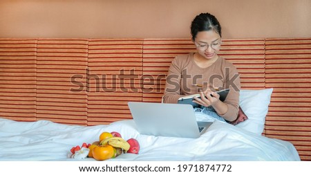Picture of tourists used laptop and eating fruits on the bed in the luxury hotel room, healthy food concept.