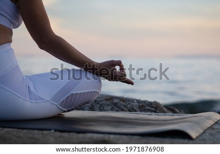 Close Gyan Mudra. Yoga on the beach. Lotus yoga pose. Yogi woman sitting on the sand, meditating, practicing yoga and pranayama with gyan mudra. Sunset time. Yoga lifestyle.