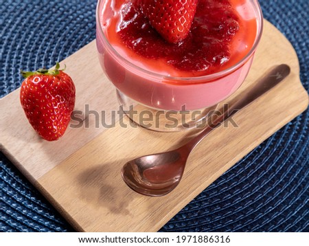 Tasty strawberry mousse in glass with jam on top