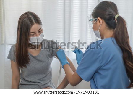 Covid-19,coronavirus hand of young woman nurse,doctor giving syringe vaccine, inject shot to asian arm's patient. Vaccination, immunization or disease prevention against flu or virus pandemic concept.