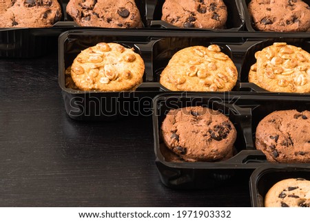 The rows of plastic boxes with mix chocolate cookies with copy space, Ds=ark food photo of dark and white chocolate cookies on the black wooden table.