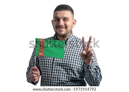 White guy holding a flag of Turkmenistan and shows two fingers isolated on a white background.