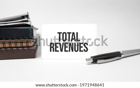 Paper plate, glasses, notepad in stack,pen and text total revenues on business card