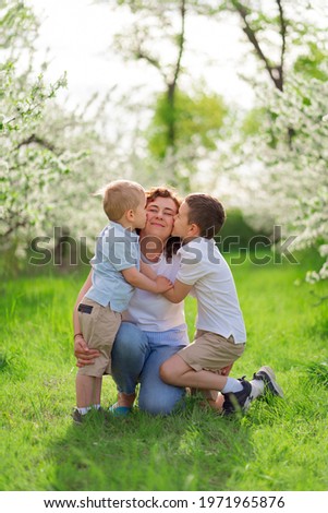 A mother with sons kiss and cuddle in flowering garden. outdoor walks are good for your health. parental care. Happy family. mother's day