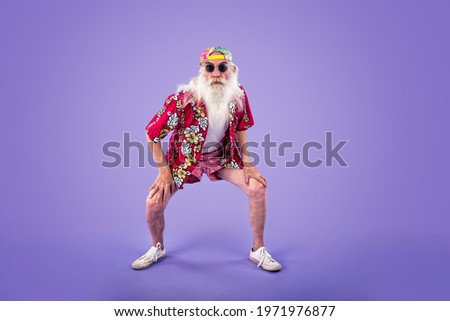 Fashionable grandfather posing with funny clothes. Senior man portraits on colored background