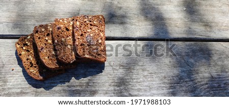 Top view of bread with various seeds (pumpkin, flax, sunflower, prunes), black rye bread, on the background of an old rustic board.