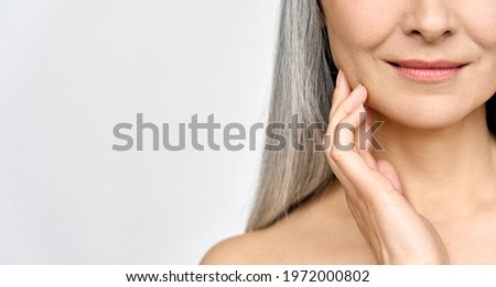 Senior older middle aged Asian woman's radiant face with perfect skin. Advertising of antiaging anti wrinkle tightening procedures skincare and makeup for glow and healthy skin. Copy space. closeup Royalty-Free Stock Photo #1972000802
