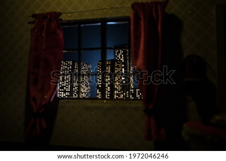 look through a window and city night view. Realistic dollhouse window and city miniature in selective focus.