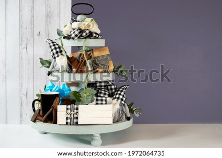Father's Day or masculine birthday. On-trend farmhouse aesthetic three tiered tray decor filled with gifts, cute black plaid gnomes, and farmhouse style stack of books mockup. Negative copy space.