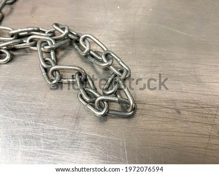 A large iron metal strong powerful shiny chain with links lies on an iron industrial table. Hand-held locksmith tools. The background.