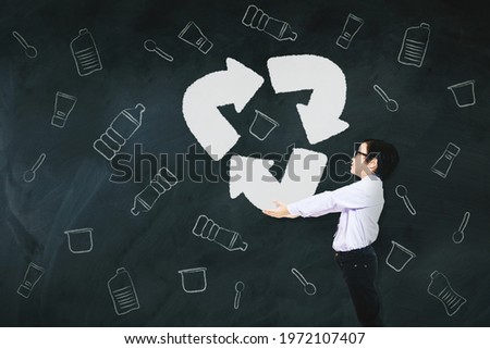 Little businessman holding recycle symbol with drawn plastic garbage background