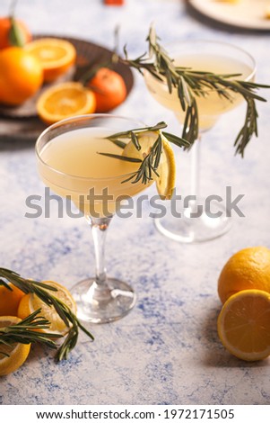 Yellow christmas alcoholic lemonade with oranges, tangerines and rosemary in margarita glasses