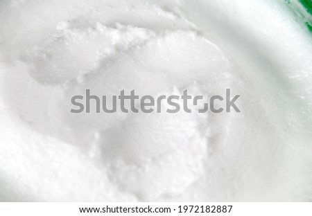 Hand cream or moisturizer, macro. Perspective view of container with white thick used cream or lotion for skin health and hydrating. Skincare background texture. Selective focus. Royalty-Free Stock Photo #1972182887