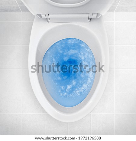 Top view of toilet bowl, blue detergent flushing in it Royalty-Free Stock Photo #1972196588