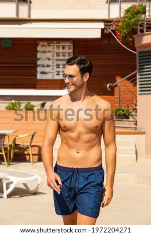 Handsome young man in swimming shorts enjoying in hot summer day