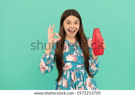 surprised kid with long hair hold shampoo bottle show ok gesture, advertisement.
