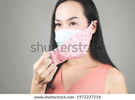 Close up image of Asian woman wearing  pink polka dot cloth mask on medical face mask  for better protection  from covid-19 outbreak. Double face masks for covid19 protection.