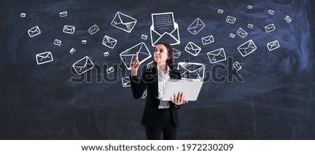 Mailing list and marketing concept with young woman with laptop on blackboard background with envelopes and letters