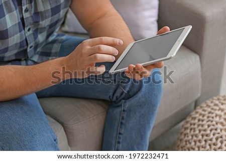 Young man with tablet computer at home, closeup