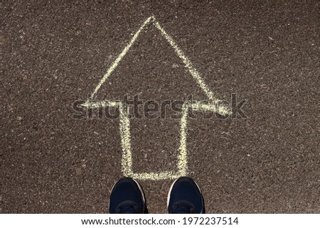 feet and drawing arrows on pavement asphalt