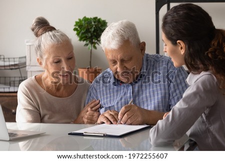 Last formality. Older family couple buying house apartment taking loan making bank deposit with help of professional manager agent. Retired spouses sign paper contract take loan sell purchase property