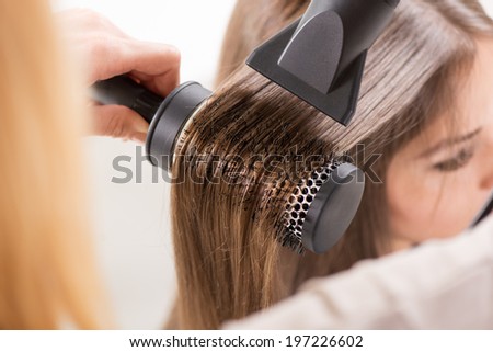 Drying long brown hair with hair dryer and round brush. Close-up. Royalty-Free Stock Photo #197226602